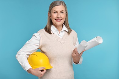 Photo of Architect with hard hat and drafts on light blue background