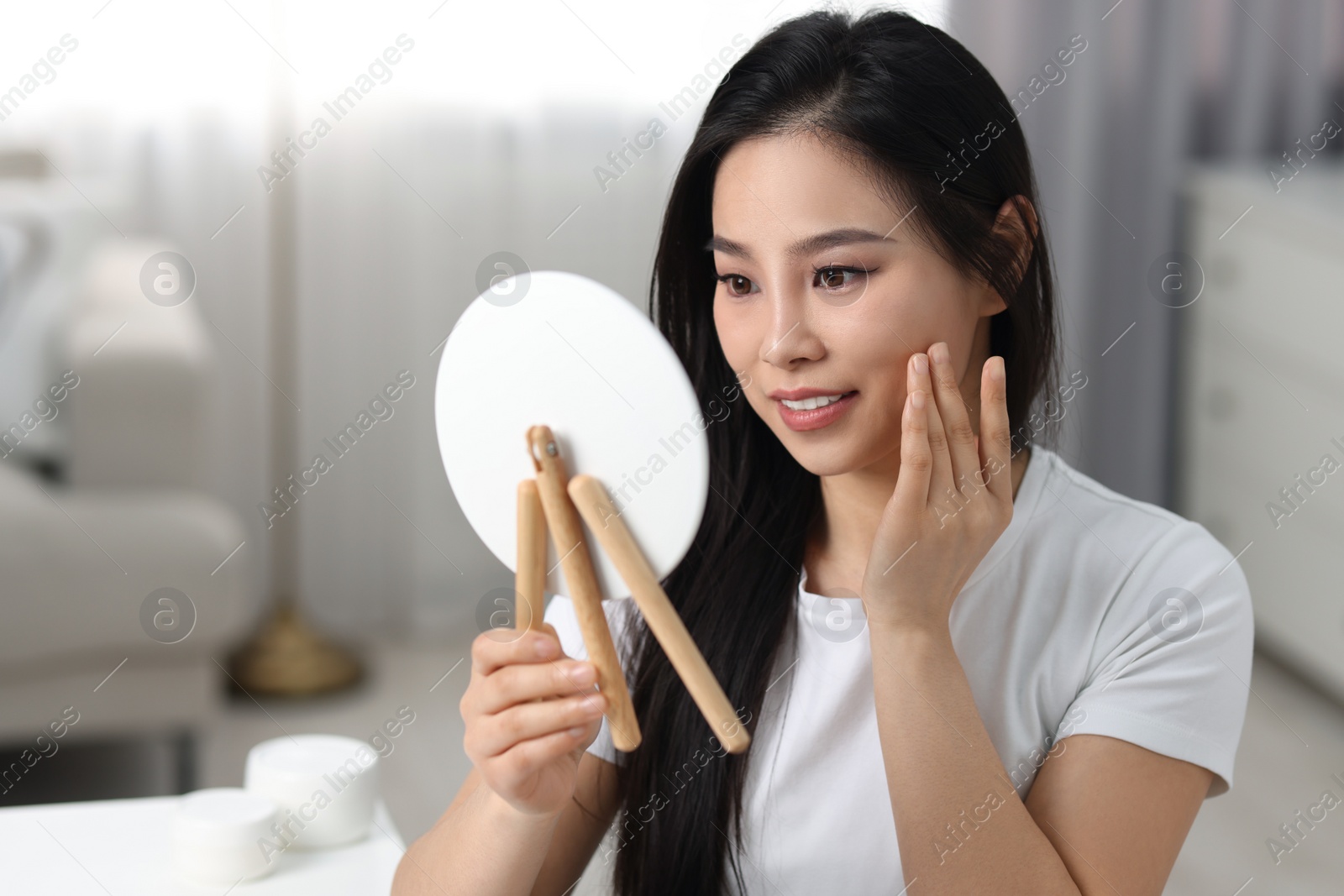 Photo of Woman with perfect skin looking at mirror indoors, space for text