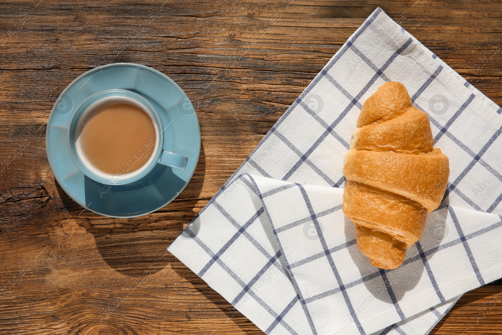 Photo of Fresh croissant and cup of coffee on wooden background, top view