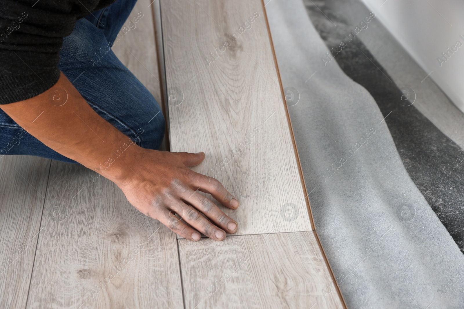 Photo of Worker installing new laminate flooring in room, closeup