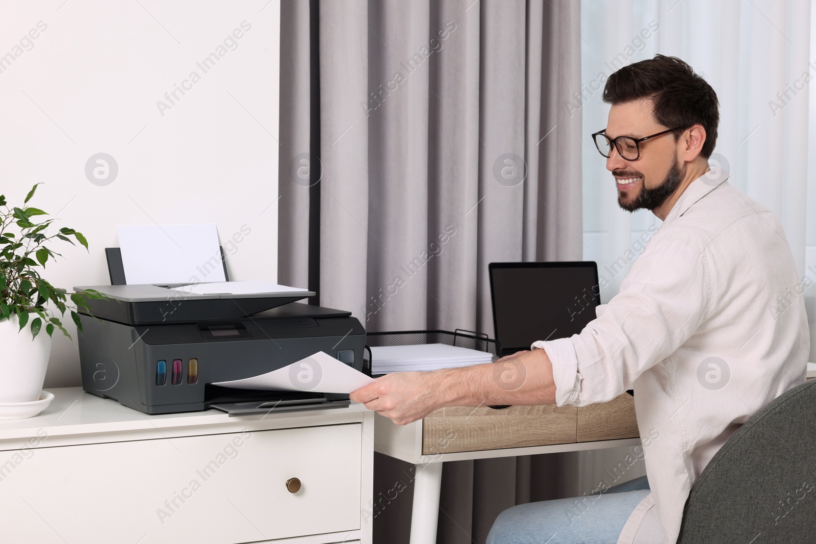 Photo of Man using modern printer at workplace indoors