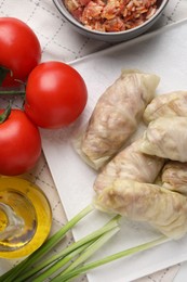 Uncooked stuffed cabbage rolls and ingredients on table, flat lay