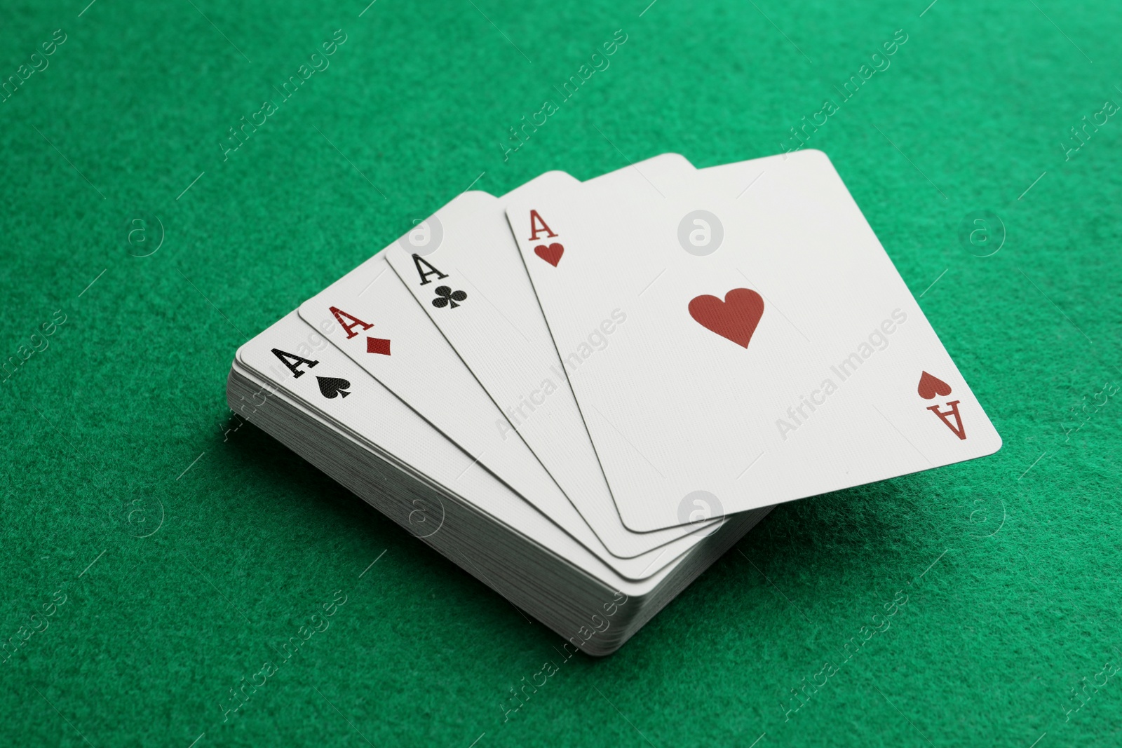 Photo of Four aces playing cards on green table, closeup. Poker game