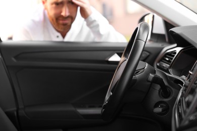 Automobile lockout, key forgotten inside, selective focus. Emotional man looking through car window