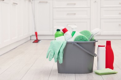 Photo of Different cleaning supplies in bucket on floor. Space for text
