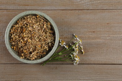 Photo of Dry and fresh chamomile flowers on wooden table, flat lay. Space for text