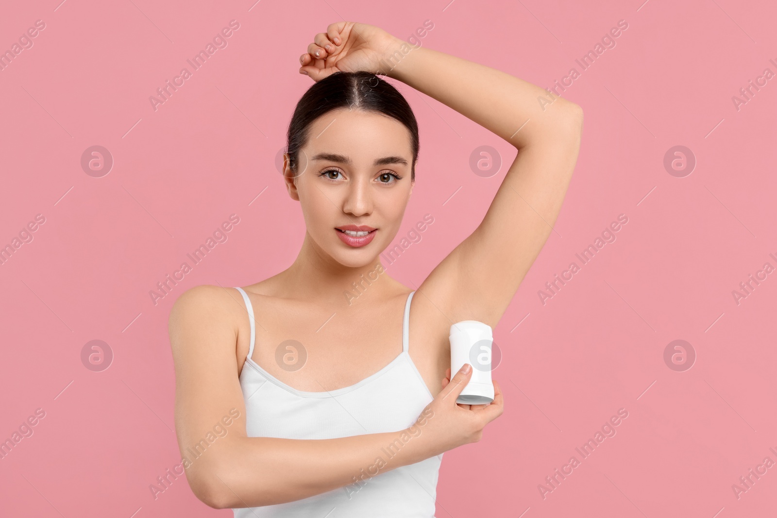 Photo of Beautiful woman applying deodorant on pink background