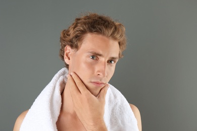 Photo of Young man touching his soft skin after shaving on gray background