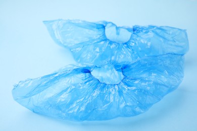 Photo of Pair of medical shoe covers on light blue background