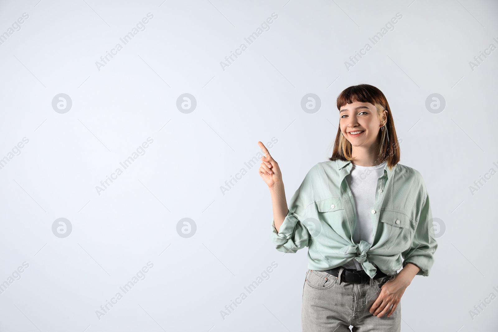 Photo of Beautiful young girl pointing on white background. Space for text