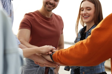 Group of happy people holding hands together, outdoors