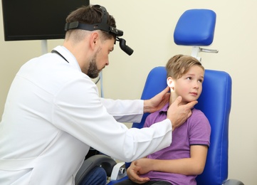 Photo of Male otolaryngologist examining little child in hospital