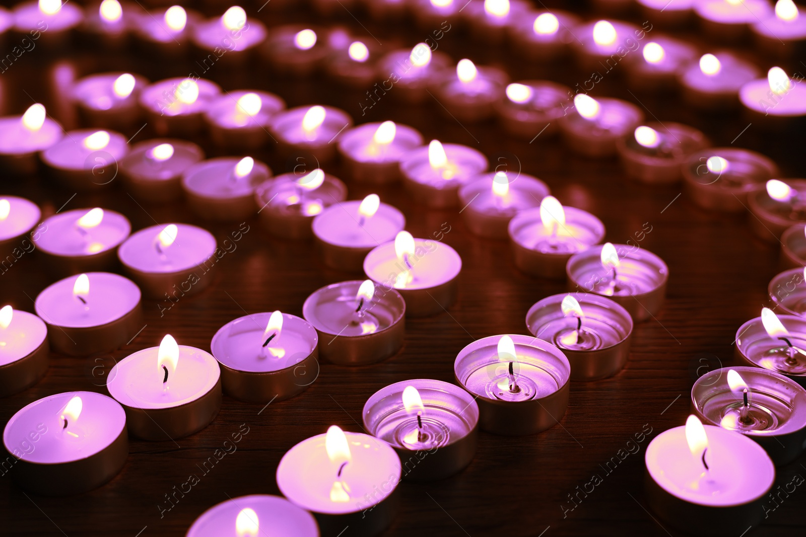 Image of Beautiful burning violet candles on black background. Funeral attributes