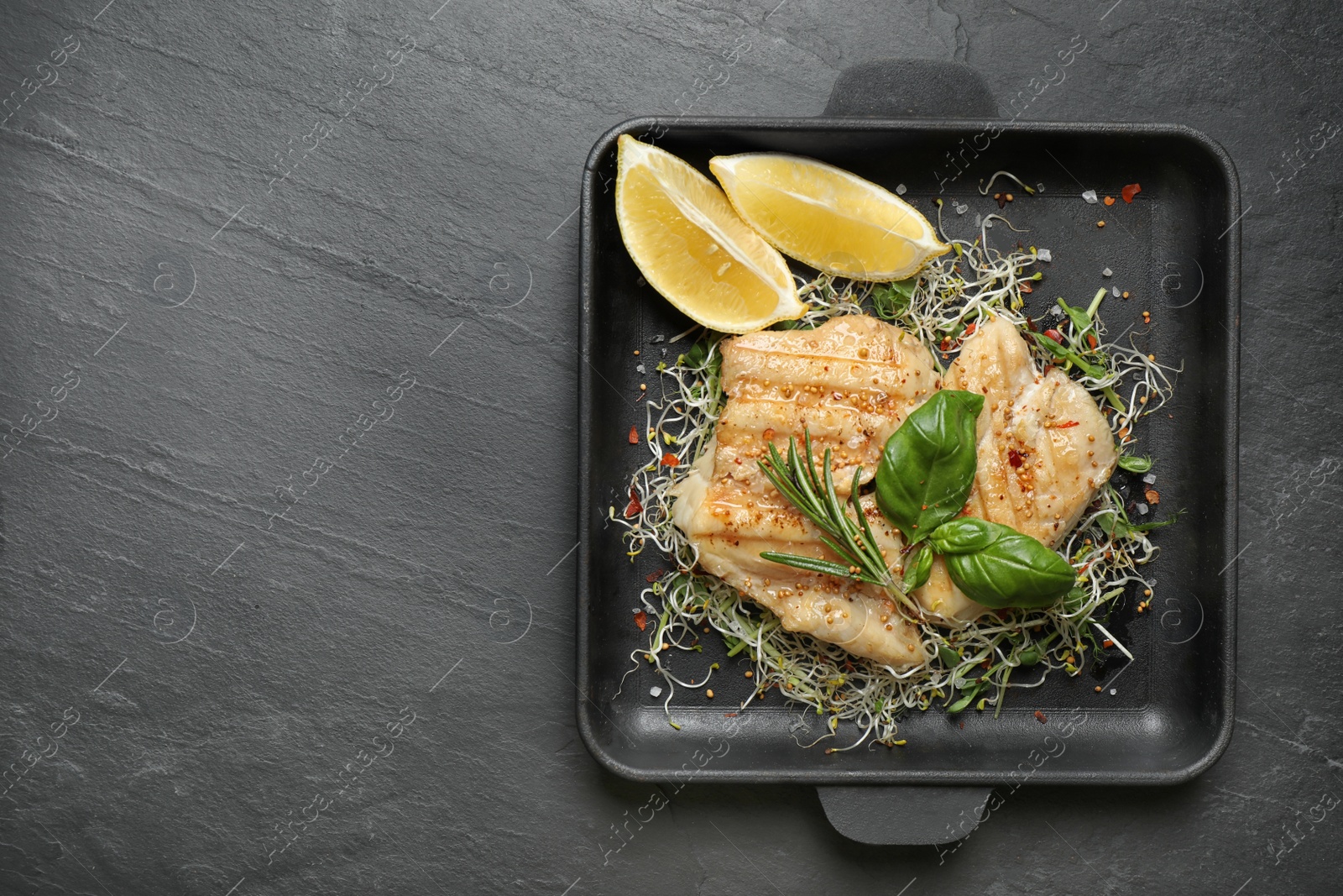 Photo of Tasty grilled fish on black table, top view. Space for text