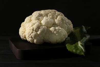 Photo of Fresh raw cauliflower on black wooden table, closeup