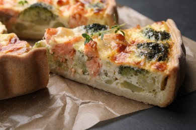 Photo of Delicious homemade quiche with salmon and broccoli on parchment paper, closeup