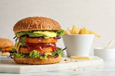 Photo of Vegan burger with carrot patties served on table against light background. Space for text