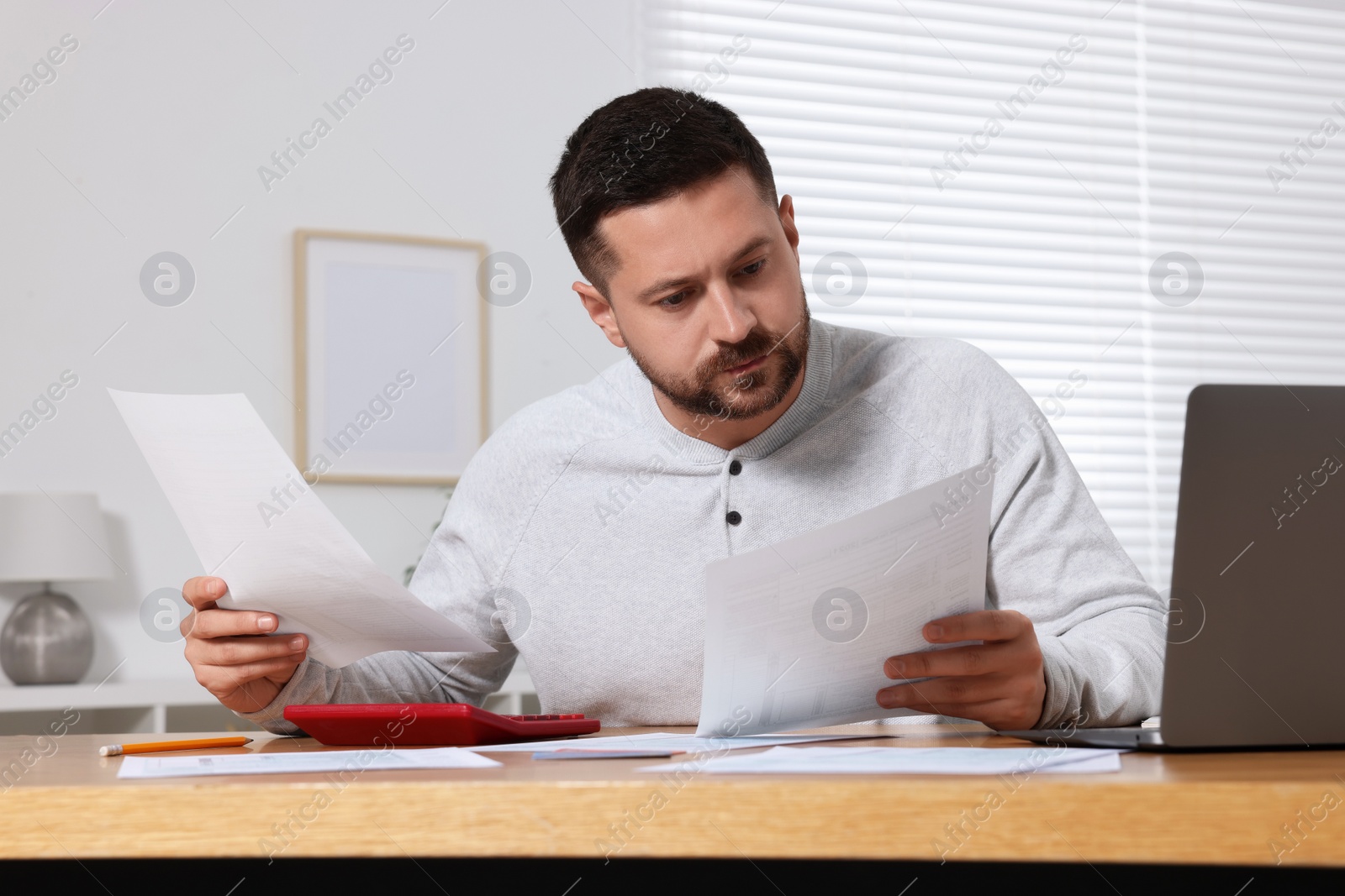 Photo of Man doing taxes at table in room