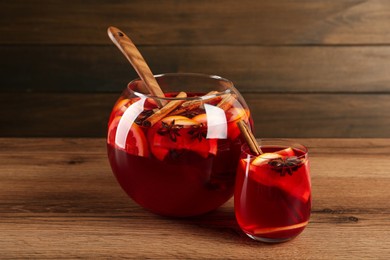 Photo of Glass and bowl of delicious aromatic punch drink on wooden table