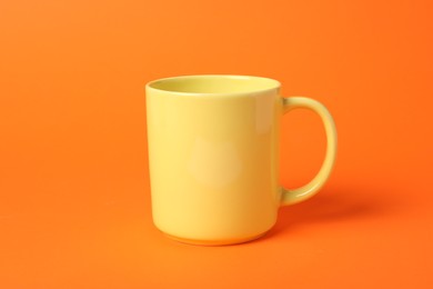 Photo of One yellow ceramic mug on orange background