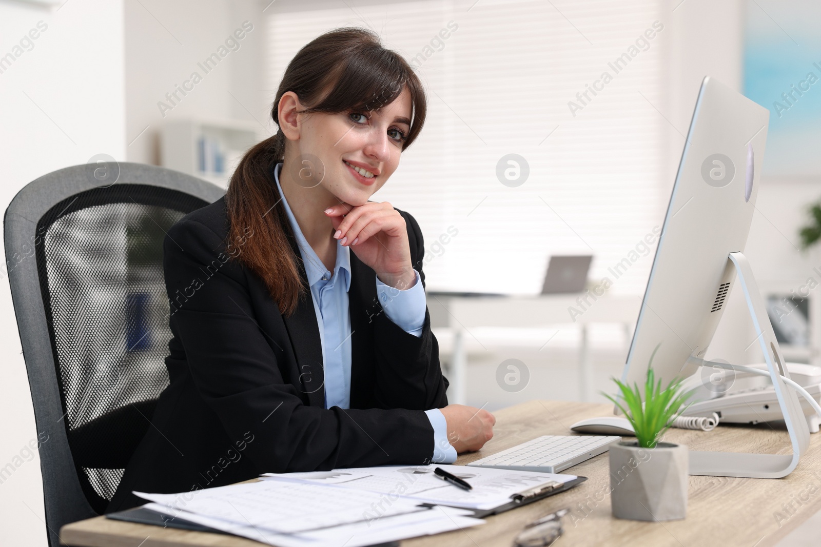 Photo of Portrait of smiling secretary at table in office