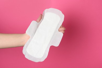 Photo of Woman holding sanitary napkin on pink background, closeup