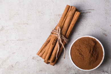 Photo of Aromatic cinnamon sticks and powder on light table, flat lay. Space for text