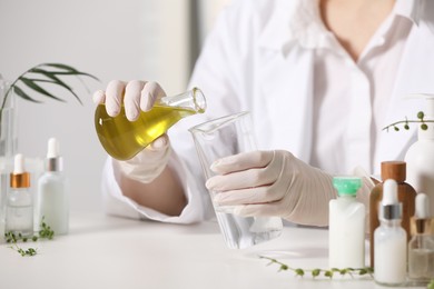 Photo of Dermatologist developing cosmetic product at white table indoors, selective focus