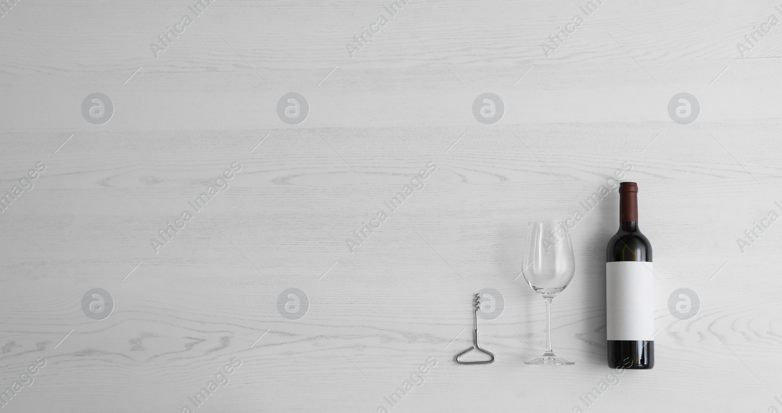 Photo of Flat lay composition with bottle of wine and elegant glass on white wooden background. Space for text