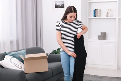 Happy woman with stylish black jeans at home. Online shopping