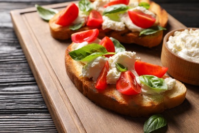 Photo of Toasted bread with tasty cream cheese and tomatoes on wooden board