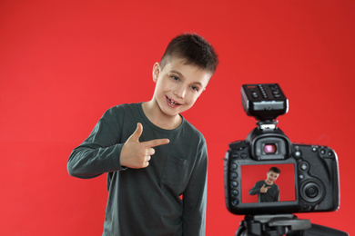 Cute little blogger recording video on red background