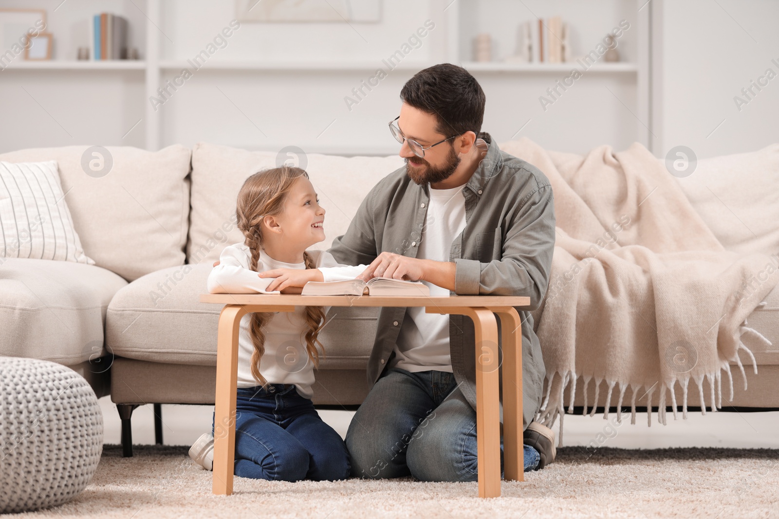 Photo of Girl and her godparent reading Bible together at table in room