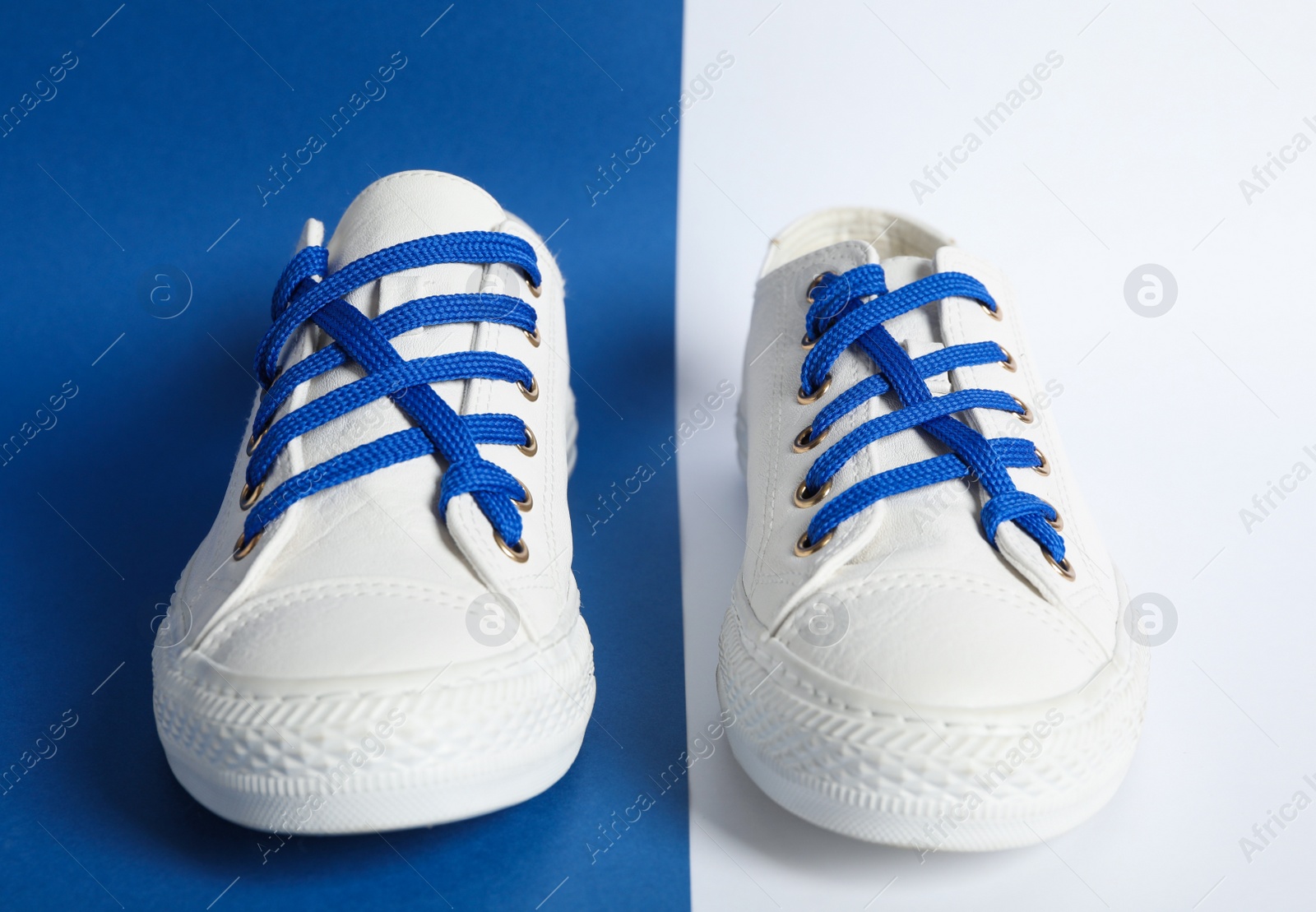 Photo of Pair of stylish shoes with blue laces on color background