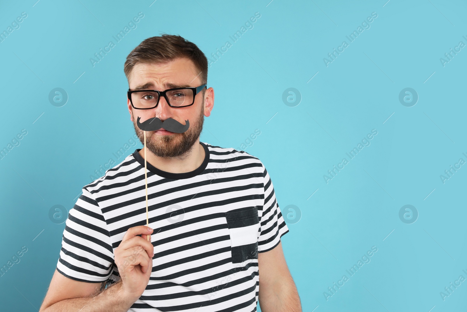 Photo of Funny man with fake mustache on turquoise background, space for text