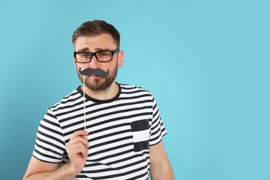 Funny man with fake mustache on turquoise background, space for text