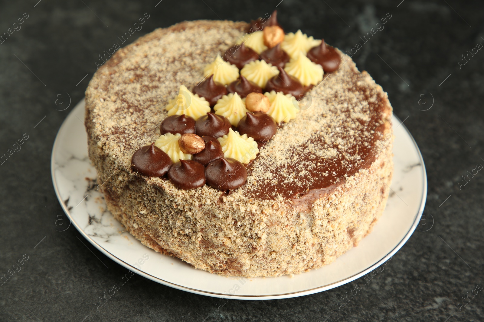 Photo of Delicious Kyiv Cake with cream and hazelnuts on black table, closeup