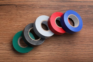 Photo of Colorful insulating tapes on wooden table, flat lay