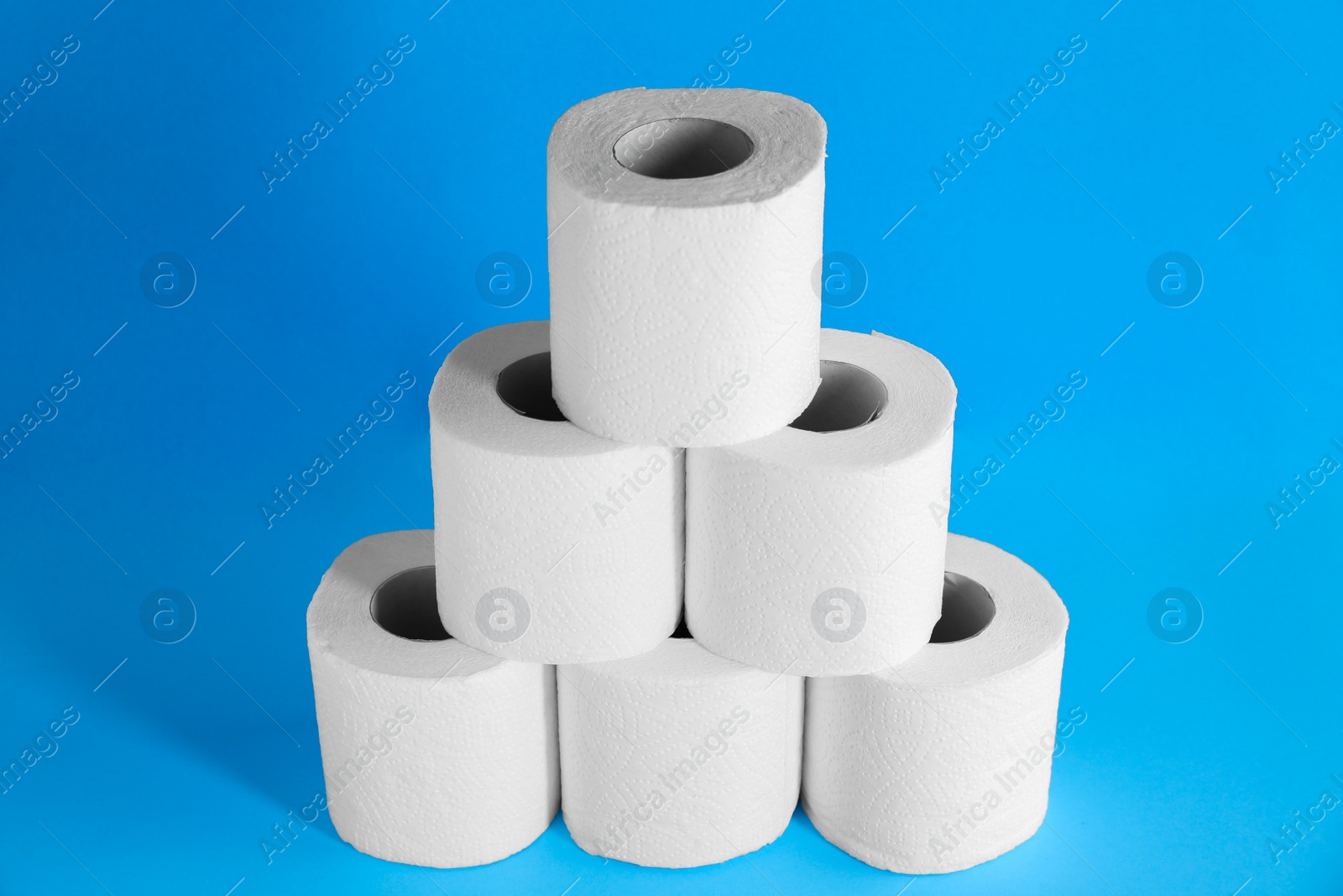 Photo of Pyramid of toilet paper rolls on light blue background