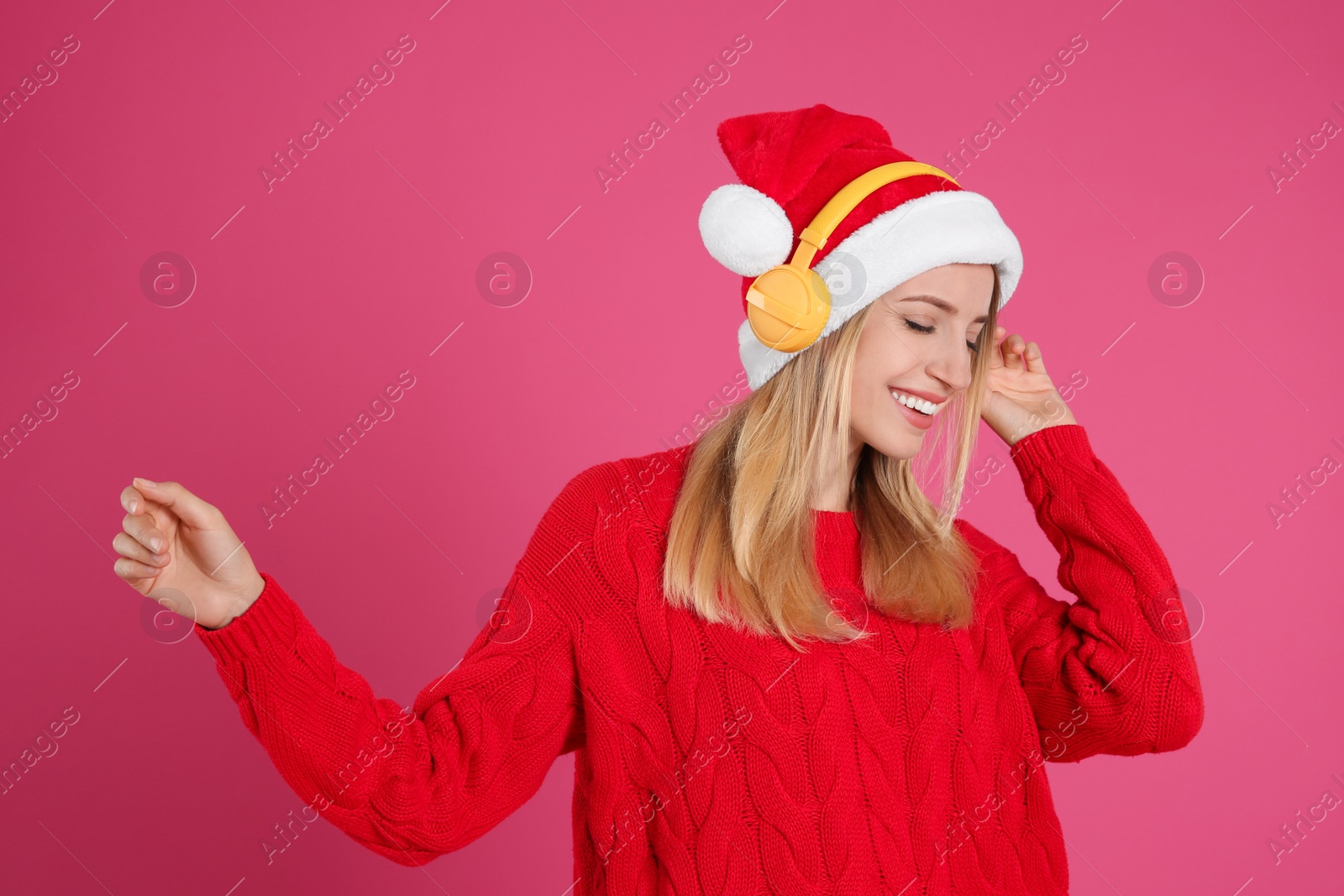 Photo of Happy woman with headphones on pink background. Christmas music