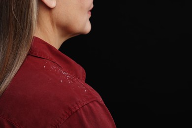 Photo of Woman with dandruff on her shirt against black background, closeup. Space for text