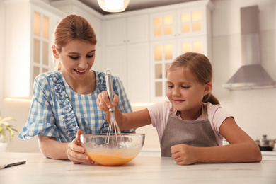 Photo of Mother and daughter making dough together in kitchen