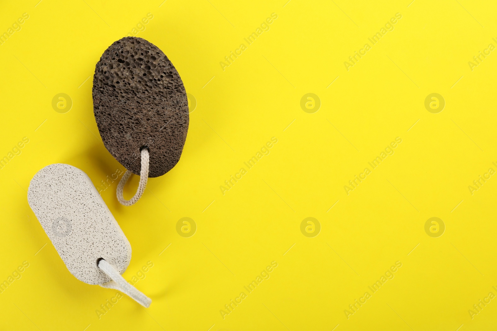 Photo of Pumice stones on yellow background, flat lay. Space for text
