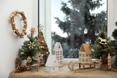 Many beautiful Christmas decorations and small fir trees on window sill indoors
