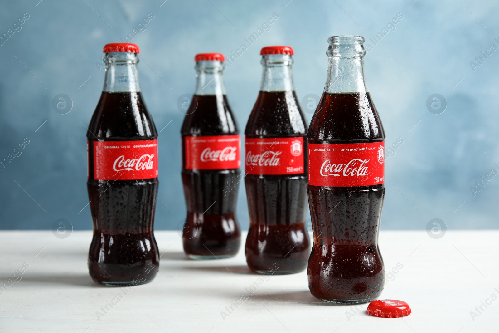 Photo of MYKOLAIV, UKRAINE - NOVEMBER 15, 2018: Bottles of Coca Cola on table against color background