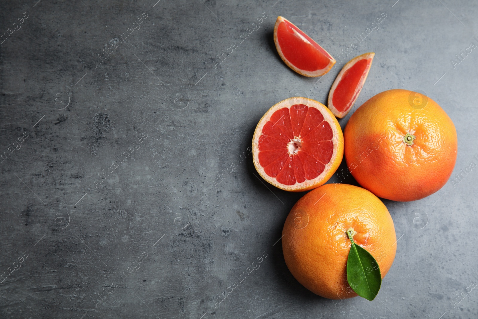 Photo of Fresh tasty grapefruits on grey background, top view with space for text