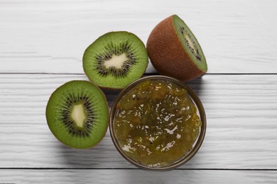 Photo of Jar with delicious kiwi jam and fresh fruits on white wooden table, flat lay