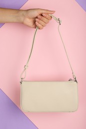 Photo of Woman holding stylish beige bag on color background, closeup