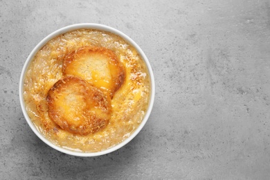 Photo of Tasty homemade french onion soup on grey table, top view. Space for text