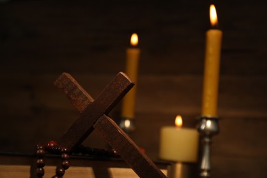 Photo of Wooden cross, Bible, rosary beads and church candles against blurred background, space for text